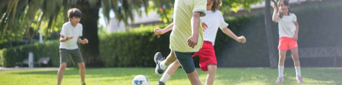 Group of kids enjoying a game of soccer on a grassy field in Portugal.