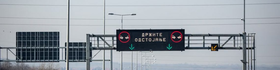 View of a highway with a digital traffic sign under a clear blue sky.